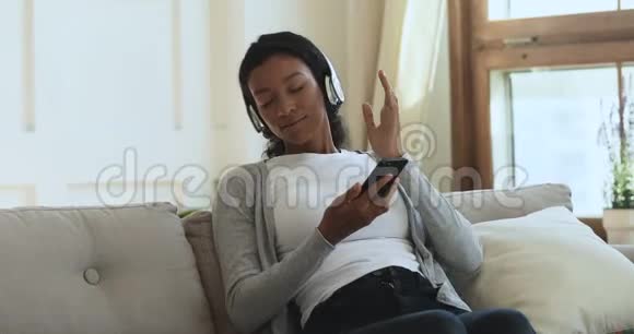 穿着无线耳机听移动音乐的非洲女性放松视频的预览图