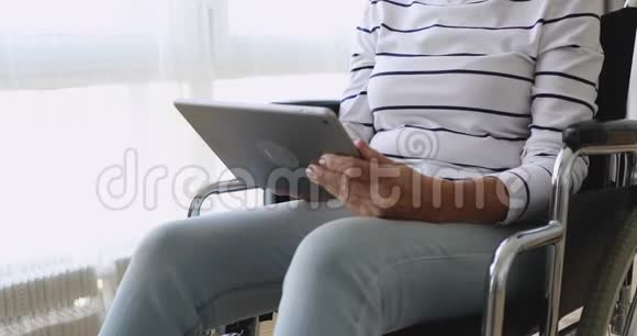 残疾老人坐在轮椅上使用数码平板电脑特写镜头视频的预览图