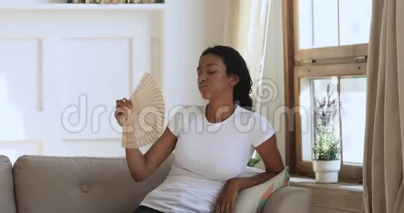 过热恼羞成怒的非洲女人在家里用风扇感到热视频的预览图
