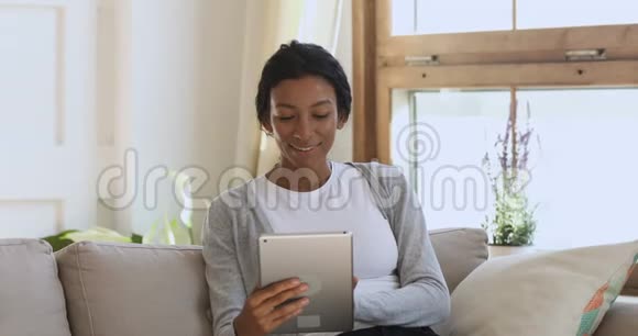 令人惊讶的是年轻的非洲妇女在家里的平板电脑上获胜视频的预览图