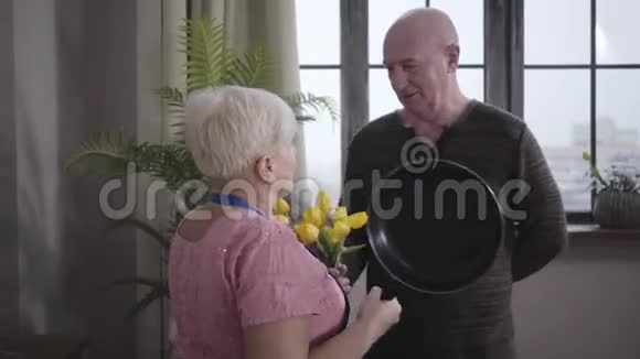 可笑的白人奶奶用煎锅威胁她丈夫微笑着成熟的秃头男人用一个视频的预览图