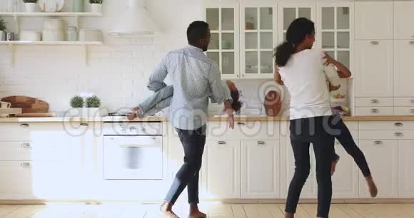 快乐的非洲父母抱着孩子们在厨房里开心地跳舞视频的预览图