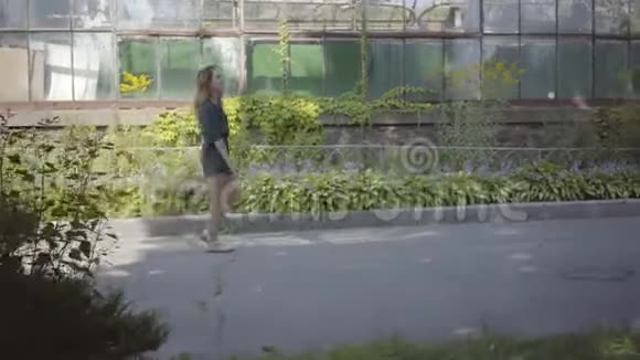 自信美丽的年轻女子走在老楼捧着一束野花夏季概念视频的预览图