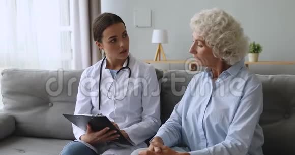 年轻女性护士在剪贴板上与老年病人交谈视频的预览图