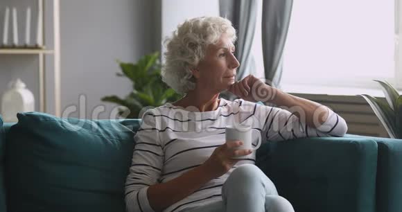 严肃体贴的老妇人看着一边喝茶沙发视频的预览图