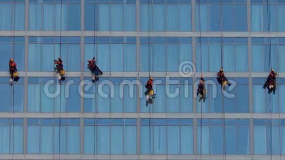 一群高维修工人悬在电线上打扫一座高楼的窗户视频的预览图