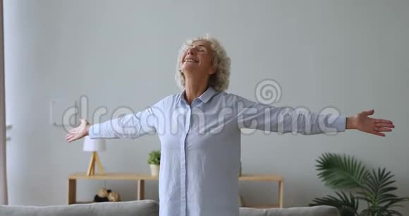 喜出望外的老太太张开双臂站在客厅里视频的预览图
