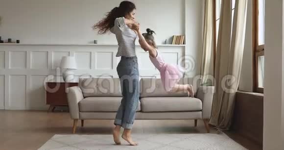 活跃的妈妈在客厅里举起旋转的小女儿跳舞视频的预览图
