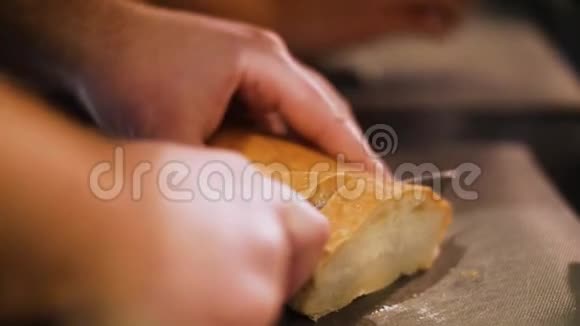 男人的特写他的手在桌子上切白面包慢动作视频的预览图