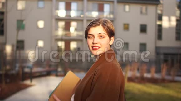 一个漂亮的年轻女子在日落时在一栋大公寓楼的背景下亲密的肖像商务女性快乐视频的预览图