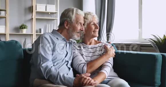 幸福的老年夫妇期待着未来在沙发上轻松交谈视频的预览图
