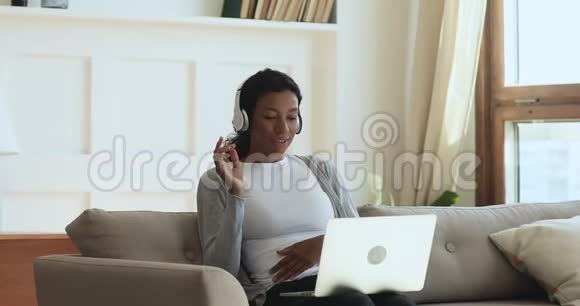 快乐的非洲女人戴着耳机在笔记本电脑上打视频电话视频的预览图