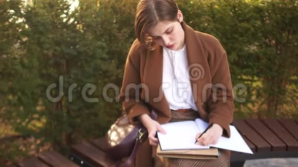 秋季春季考试学生休息期间返校一个年轻的女学生在院子里写摘要视频的预览图