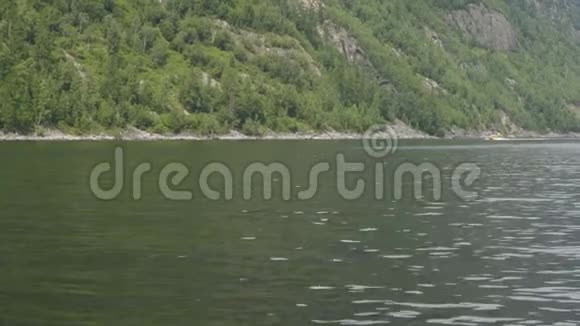 从一艘在波浪上晃动的摩托艇上拍摄一条经过的黄色小船视频的预览图