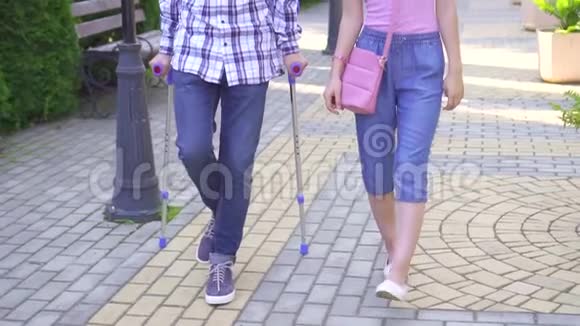拄着拐杖断腿的年轻亚裔男子与公园里的年轻亚裔女子亲密地交流视频的预览图