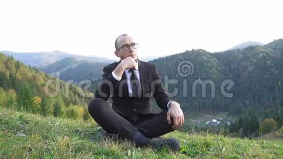 穿西装戴眼镜的人盘腿坐在山上无法掩饰自己的快乐视频的预览图