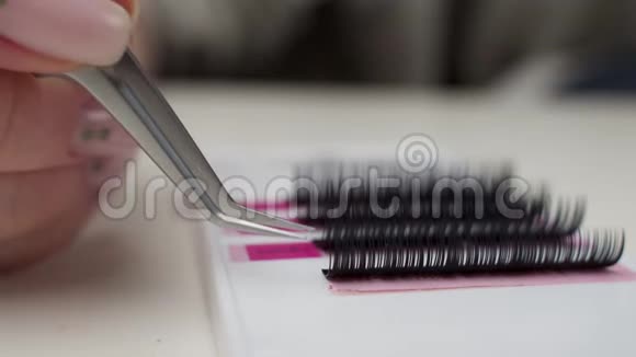 睫毛延长程序特写一位大师在工作时的人工睫毛延伸材料主人的手视频的预览图