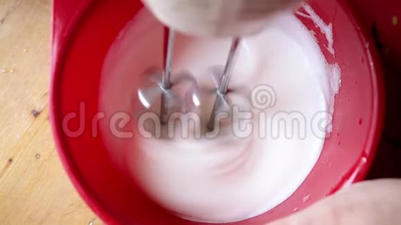 家庭主妇把鸡蛋泡沫和食品处理机混合起来用于糕点慢镜头视频的预览图