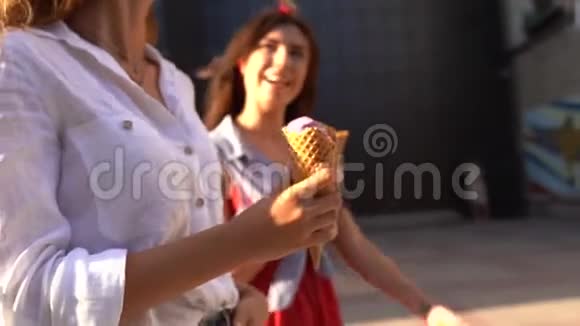 一个女人和她的朋友一起走着手里拿着一张冰淇淋锥两位在户外吃冰淇淋的年轻女性视频的预览图