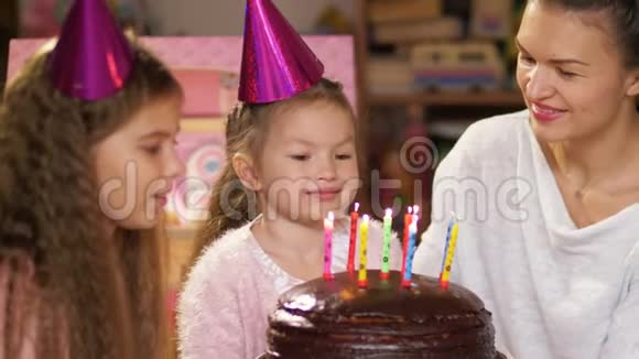 快乐的小女孩和家人一起庆祝生日她的母亲和十几岁的妹妹帮忙吹灭蜡烛视频的预览图