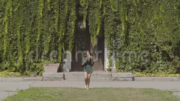 自信美丽的年轻女子走向镜头微笑着捧着一束野花在绿色的夏天视频的预览图