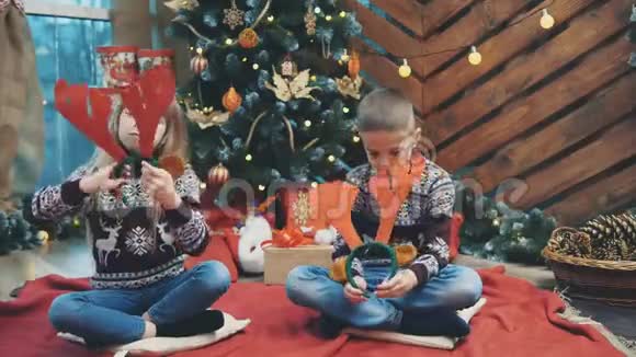 可爱的4k视频兄妹戴着驯鹿角享受在一起的时间在杉树在圣诞节晚上视频的预览图