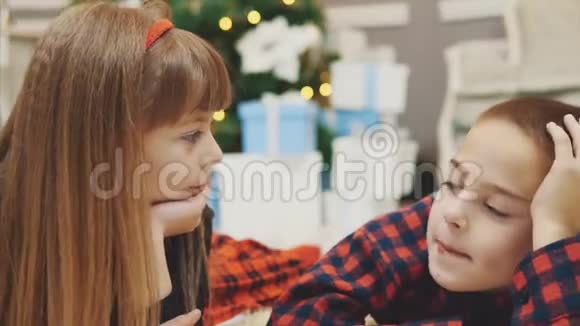 特写4k视频可爱的小朋友一起度过愉快的时光在圣诞树附近的地毯上交流视频的预览图