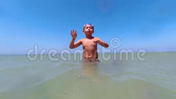在一个美丽的夏日里一个小男孩在沙滩上泼水嬉戏的慢镜头视频的预览图