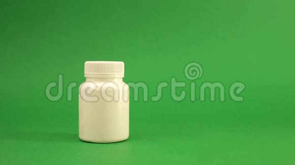 手拿白色包装药丸放在绿色背景上视频的预览图