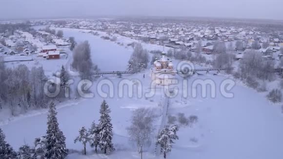 白雪皑皑的早晨飞过村庄东正教教堂桥上人们走了4K视频的预览图