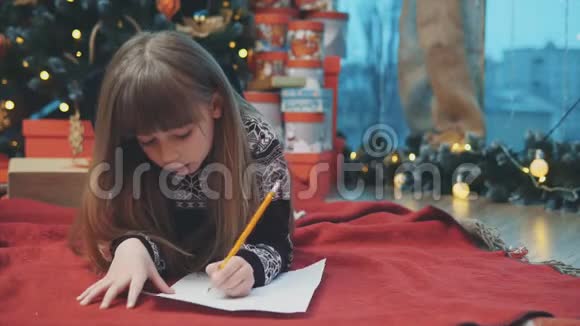 受启发的孩子躺在圣诞树下的毯子上给诺德杆写着信息看上去既高兴又有希望视频的预览图
