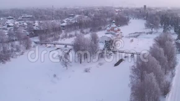 白雪皑皑的早晨飞过村庄东正教教堂桥上人们走了4K视频的预览图