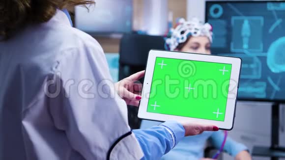 女医生在现代神经科学设施里看平板电脑绿色屏幕视频的预览图