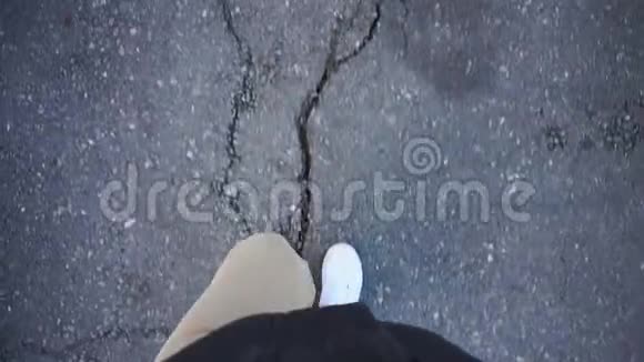 一名男子光天化日之下穿着白色运动鞋在人行道上行走旧的方式裂缝在视频的预览图