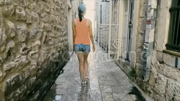 女孩游客沿着狭窄的鹅卵石街道在威尼斯和地中海建筑的老砖房中散步视频的预览图
