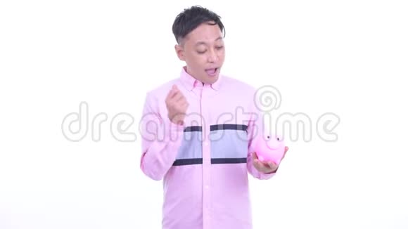 快乐的日本商人拿着储蓄罐竖起大拇指视频的预览图