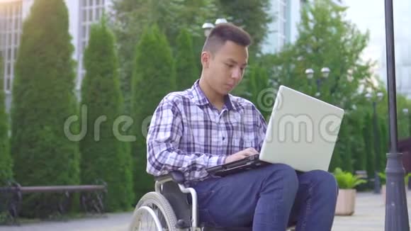 轮椅残疾的亚裔年轻人使用笔记本电脑慢动作视频的预览图