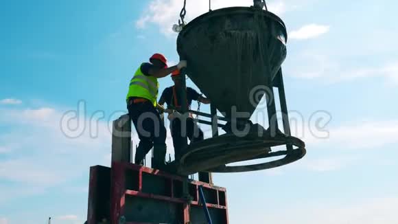 建筑工人用水泥容器工作并将其连接到起重机绳索上视频的预览图