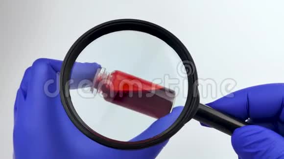 验的血样医生手里拿着一个放大镜里面放着一个带有血样的试管视频的预览图