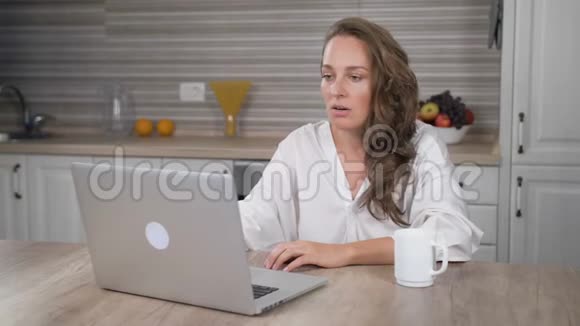 可怜的女人在厨房里用手提电脑视频的预览图
