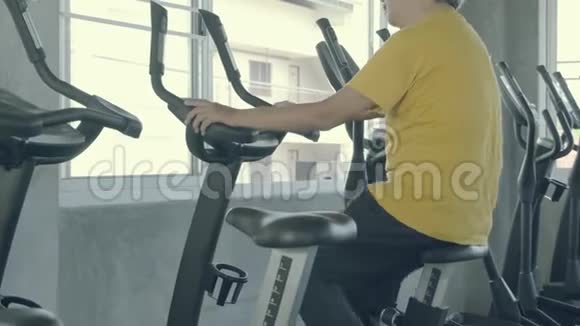 亚洲老年男子有氧运动骑自行车运动健身为健康着想视频的预览图