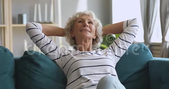快乐轻松的老妇人坐在舒适的沙发上休息着做梦视频的预览图