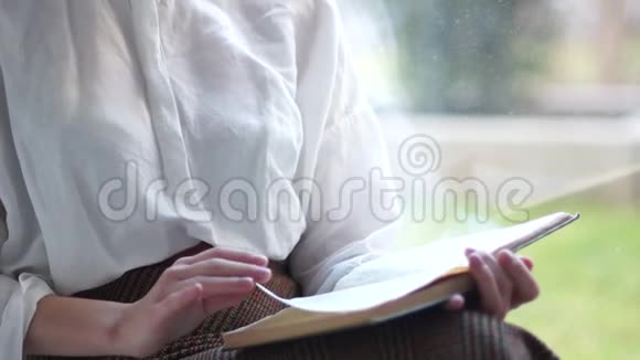 假期的女学生坐在家窗前读一本书一个可爱的短发女孩的肖像视频的预览图