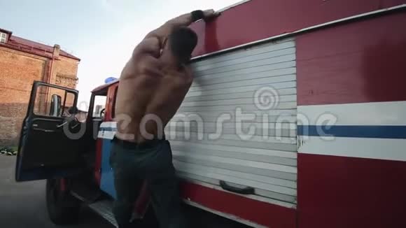 肌肉发达的年轻人拿着消防车的车顶抬起腿训练腹部肌肉视频的预览图