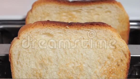烤面包从粉红色背景的白色烤面包机上跳出来特写视频的预览图