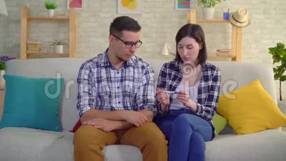 年轻体贴的已婚夫妇坐在客厅里想着家里的补给视频的预览图