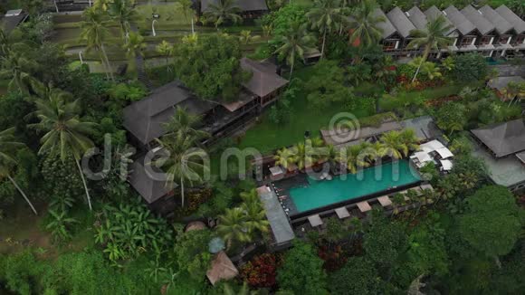 酒店豪华游泳池的空中景观热带丛林和棕榈树的草顶别墅豪华别墅视频的预览图