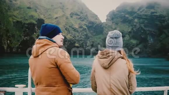 年轻的旅行夫妇站在船上交谈欣赏冰岛美丽的风景视频的预览图