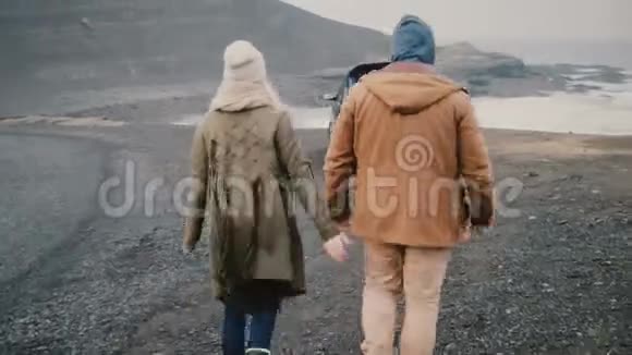 年轻快乐的一对坐车旅行迷人的男人和女人走到冰岛黑色海滩附近的车辆视频的预览图