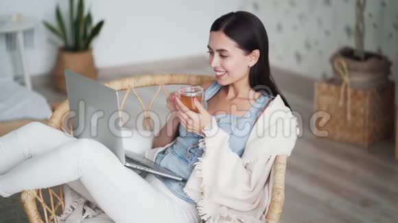 女人坐在椅子上手里拿着一杯茶看电影视频的预览图